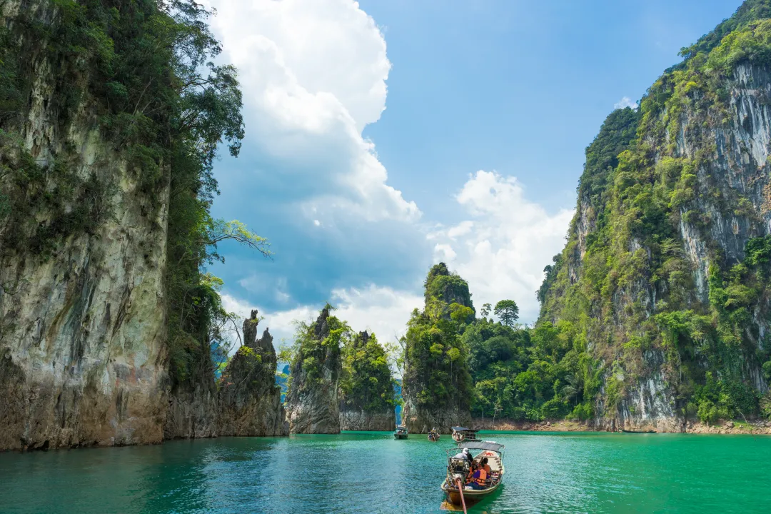 Tourist boat exploring epic limestone cliffs in huge lake in Khao Sok National Park, Chiew lan lake, Thailand.